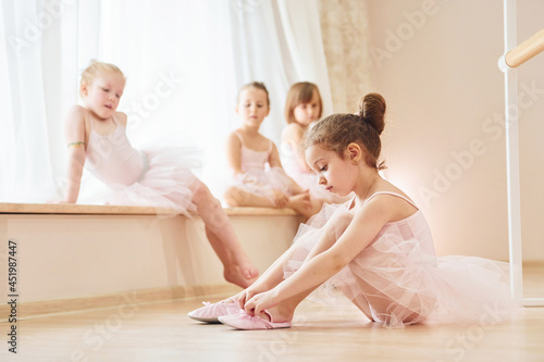 Girl sits on the floor. Little ballerinas preparing for performance by practicing dance moves