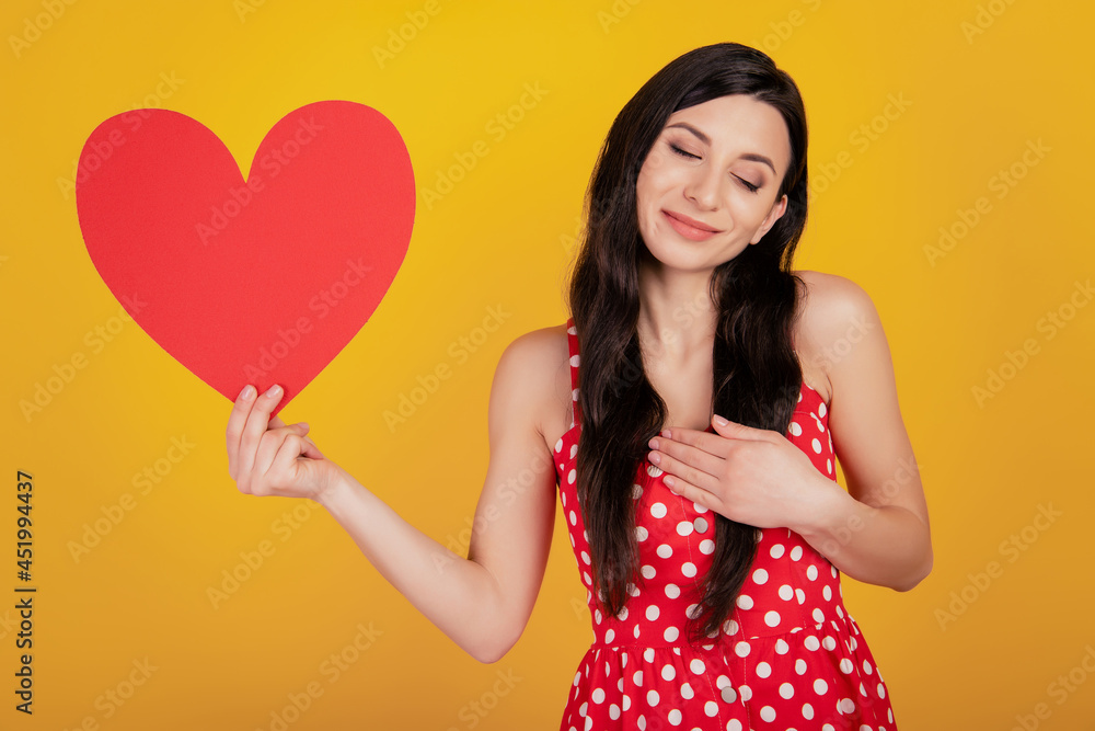 Portrait of grateful lady show heart close eyes hand chest wear dotted red dress on yellow background Portrait of grateful lady show heart close eyes hand chest wear dotted red dress on yellow background
