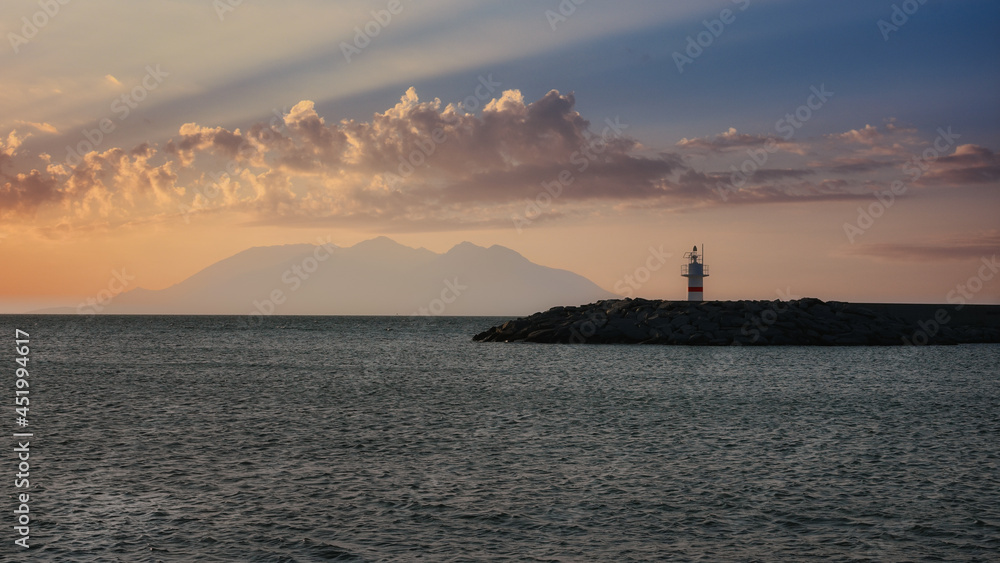 lighthouse and beach with clouds at island port