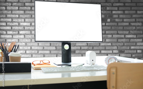 Mock up computer, headphone and office supplies on white desk with brick wall. © wattana