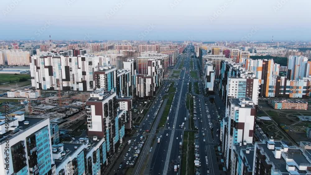 Wide long city avenue with highrise blocks of flats and cars driving on road against blue sky on sunny summer day aerial view Wide long city avenue with highrise blocks of flats and cars driving on road against blue sky on sunny summer day aerial view