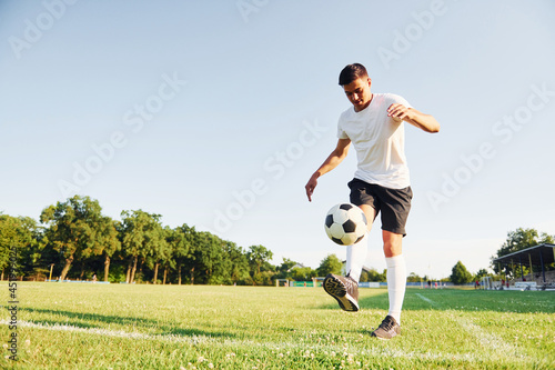 Fototapeta Naklejka Na Ścianę i Meble -  Summer daytime. Young soccer player have training on the sportive field