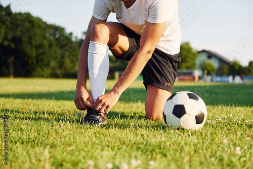 Ties laces. Young soccer player have training on the sportive field