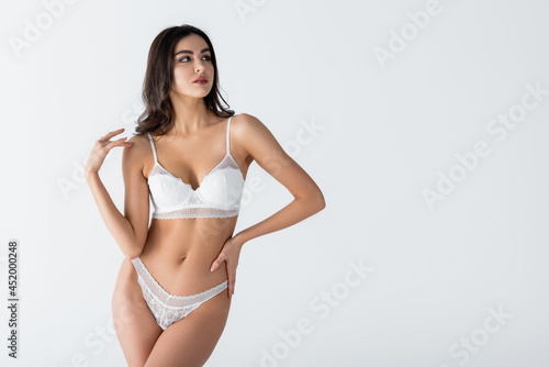 Fotografie pretty young woman in lace lingerie posing with hand on hip isolated on white