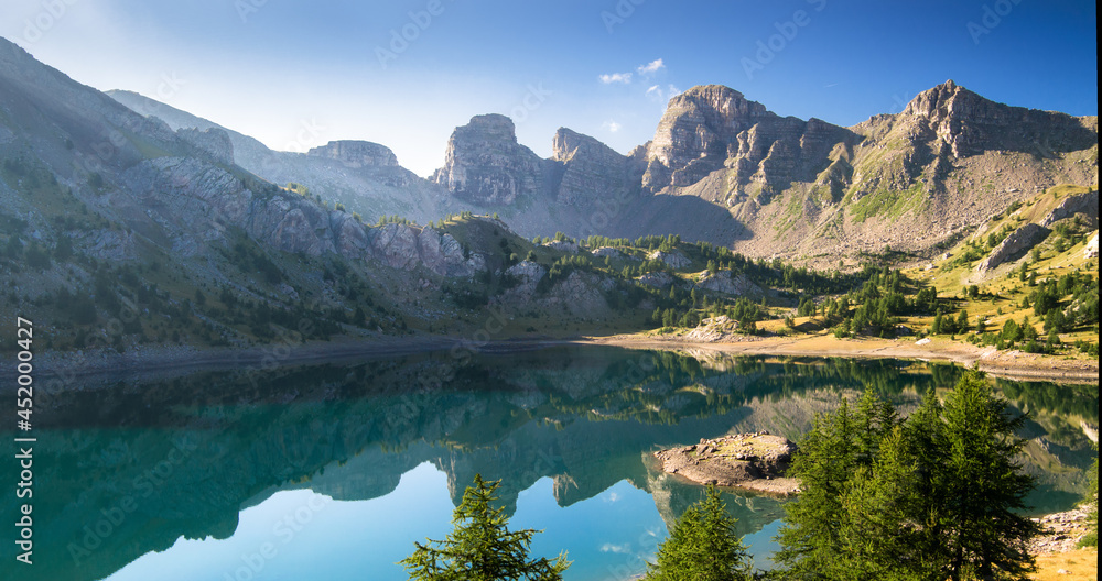 Allos lake in the morning during summer time, with mirror effect, mountains reflecting on the lake