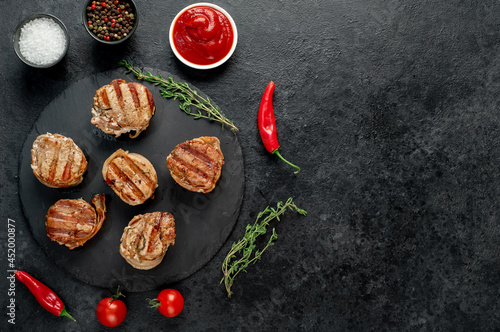 cooked grilled pork tenderloin medallions wrapped in bacon on stone background with copy space for your text 