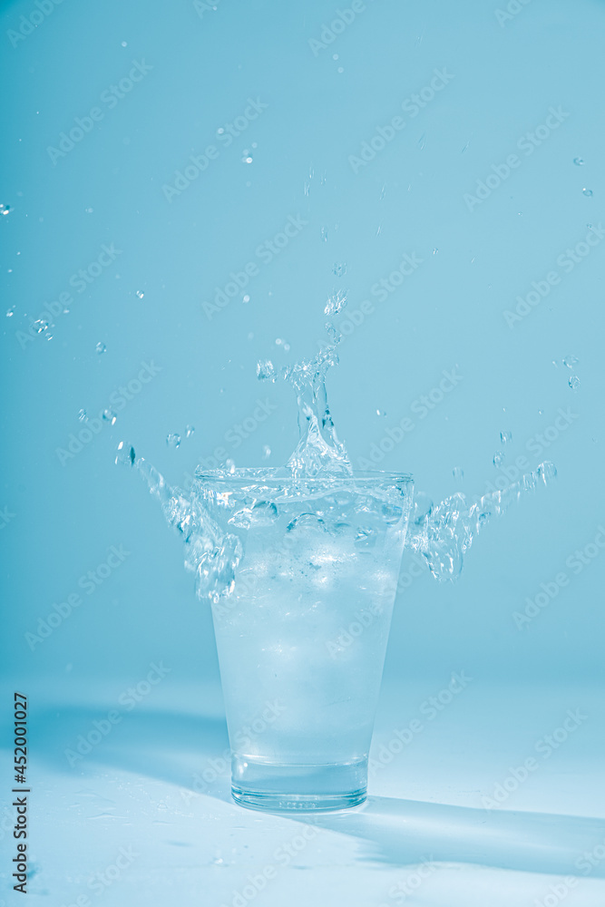 Ice cubes splashing into glass of water, isolated on white Ice cubes splashing into glass of water, isolated on white