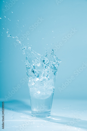 Ice cubes splashing into glass of water, isolated on white