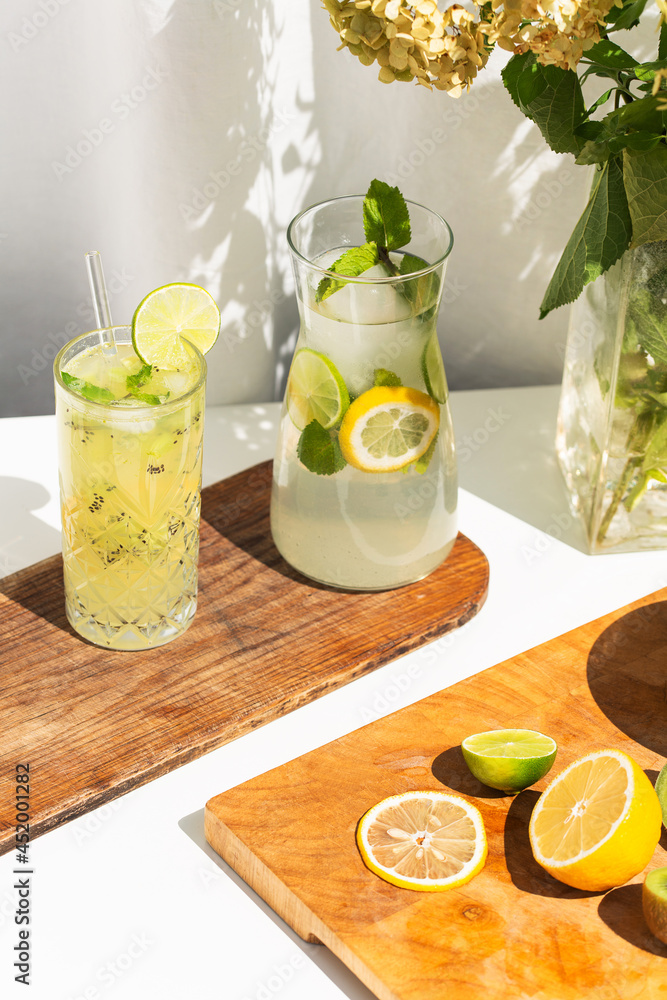 Photo of refreshing summer lemonade cocktail in glass on a wooden tray with fresh citrus lime lemon and green mint outdoors with white background Photo of refreshing summer lemonade cocktail in glass on a wooden tray with fresh citrus lime lemon and green mint outdoors with white background