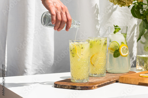 Photo of refreshing summer lemonade cocktail in glass with fresh citrus lime lemon and green mint outdoors with white background