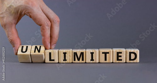 Limited or unlimited symbol. Businessman turns cubes, changes words 'limited' to 'unlimited'. Beautiful grey background, copy space. Business, limited or unlimited concept. photo