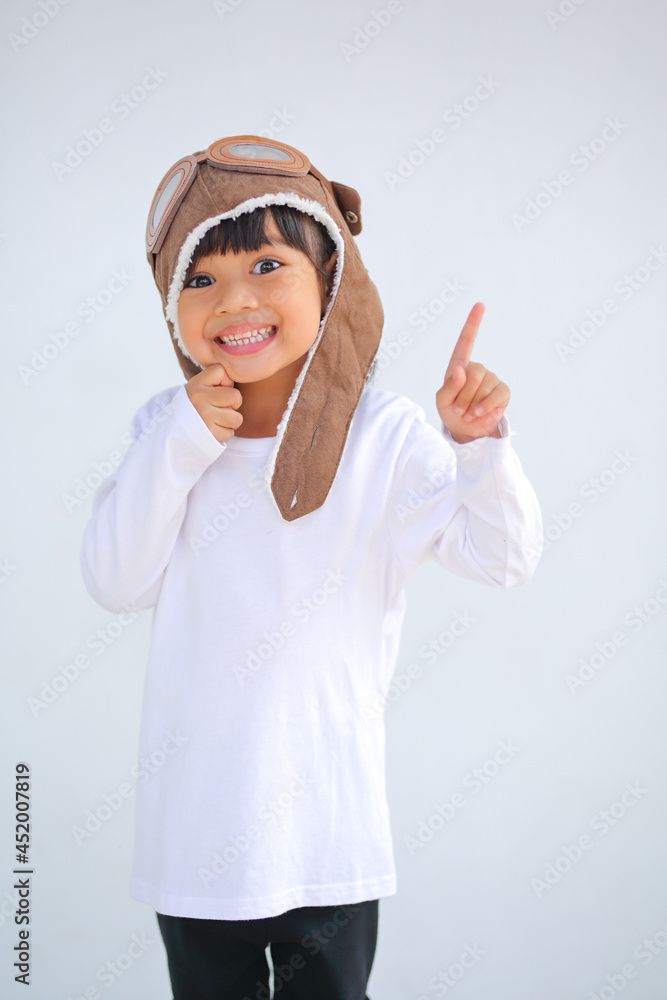 little girl dressed in a cap brown of a pilot. The child dreams of becoming a pilot which increases the development and enhances outside the classroom learning skills concept. on a white background. little girl dressed in a cap brown of a pilot. The child dreams of becoming a pilot which increases the development and enhances outside the classroom learning skills concept. on a white background.