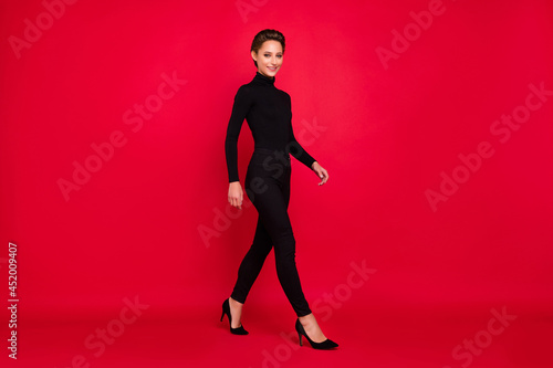 Profile side photo of young woman happy positive smile go walk step elegant isolated over red color background © deagreez