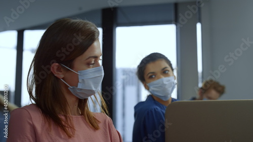 Focused businesswoman in medical mask on face working on laptop in office