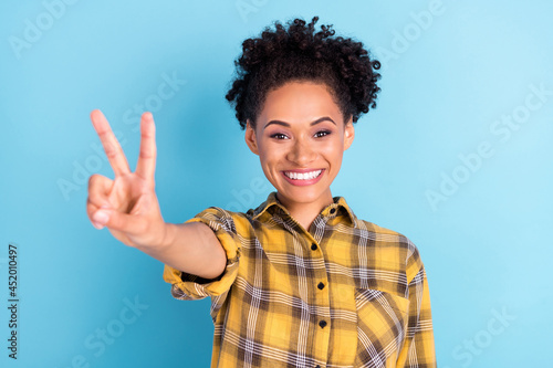 Photo portrait curly woman showing v-sign smiling isolated pastel blue color background