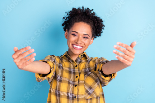 Photo of young cheerful african girl happy positive smile show hands come welcome sign isolated over blue color background photo