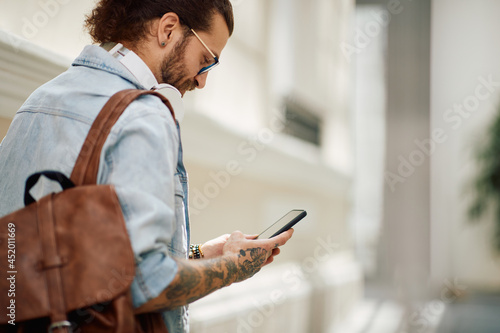 Male student reads text messaging on smart phone while going to lecture at the university.