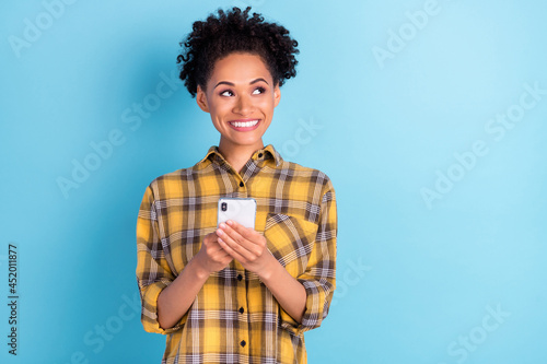 Photo portrait curly woman smiling using mobile phone looking copyspace isolated pastel blue color background