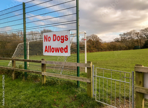 Large "No dogs allowed" sign on the fence of a football field