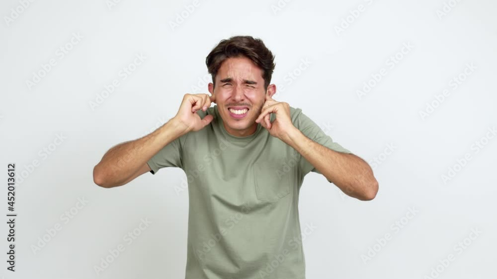 Young man covering both ears with hands. Frustrated expression over isolated background Young man covering both ears with hands. Frustrated expression over isolated background