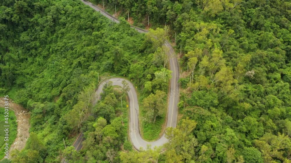Aerial view of countryside road passing through the lush greenery and foliage tropical rain forest mountain landscape in the Northern Thailand, Nan province. Aerial view of countryside road passing through the lush greenery and foliage tropical rain forest mountain landscape in the Northern Thailand, Nan province.
