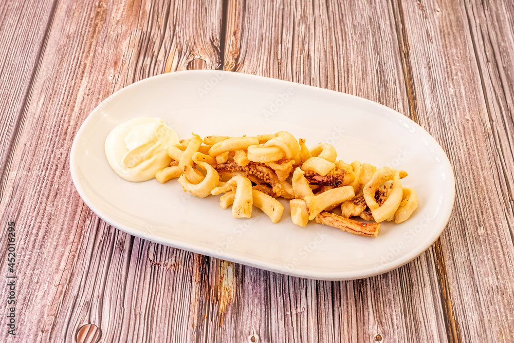 Tapa of fried squid squid accompanied by mayonnaise sauce on a white tray Tapa of fried squid squid accompanied by mayonnaise sauce on a white tray