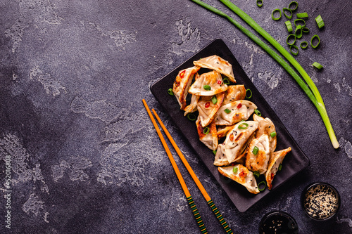 Fried dumplings served with green onions, sesame seeds and chili peppers