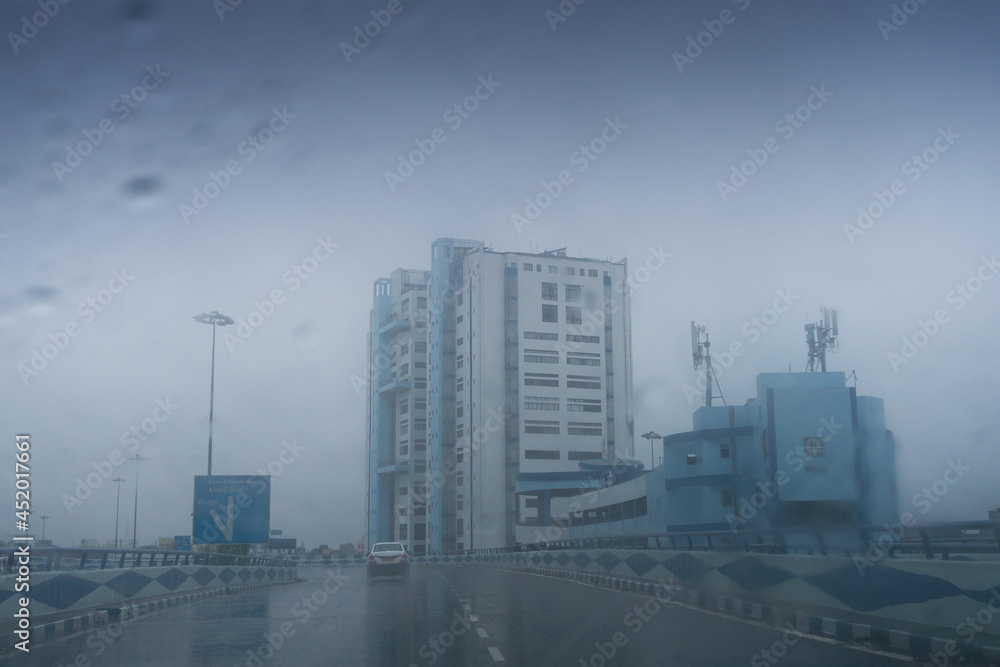 Raindrops falling on car windshield glass, abstract blurs of Nabanna building , state administrative office. Monsoon stock image of Howrah city , West Bengal, India