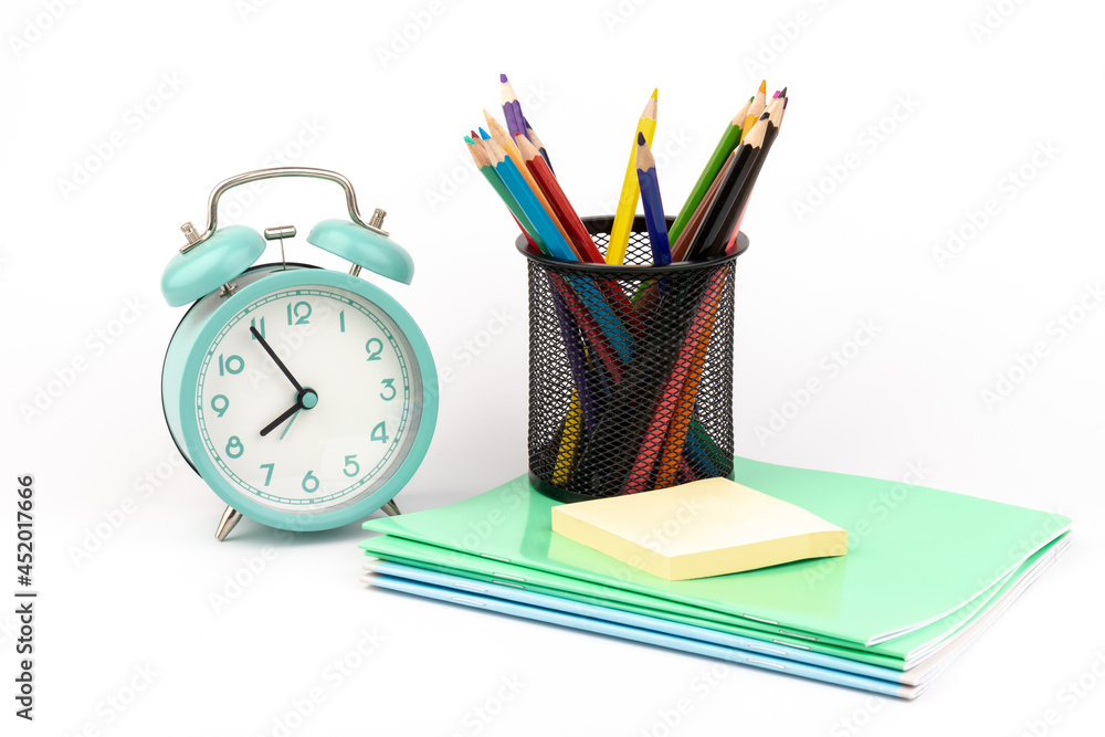 Fototapeta premium School items. Alarm clock, notebooks, pencils for drawing on a white background. Concept of education, back to school, creativity and learning. Copy space.