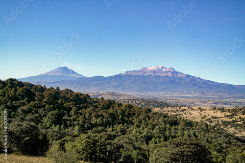 El volcán Popocatépetl y Iztaccihuatl vistos desde un bosque alejado.