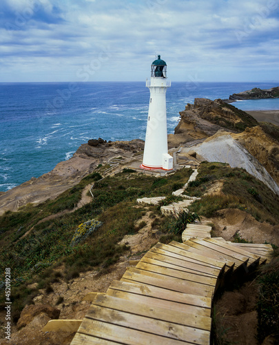 Set of wooden steps leading down to Castle Point Lighthouse on rocky cliff edge and blue pacific ocean below photo