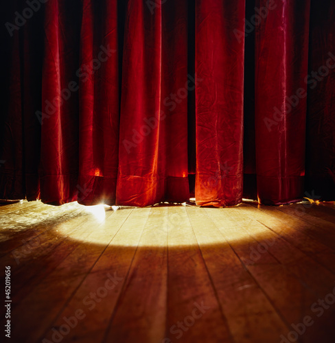 Spotlight shining on red stage curtains and wooden floor photo