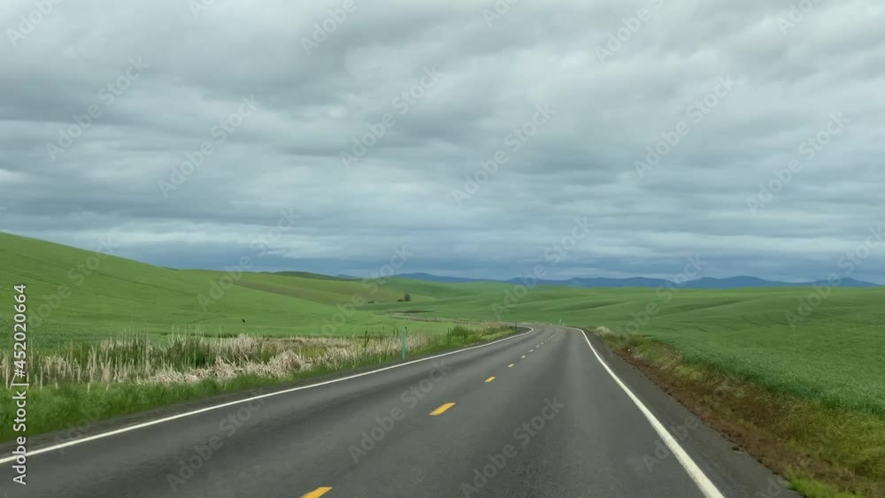 Driving down an empty two lane highway into the rolling green fields of the Palouse, Washington area. Driving down an empty two lane highway into the rolling green fields of the Palouse, Washington area.