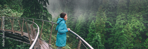 Canada Autumn travel destination in British Columbia. Asian tourist woman walking in famous attraction Capilano Suspension Bridge Park in North Vancouver. Canadian vacation banner. photo
