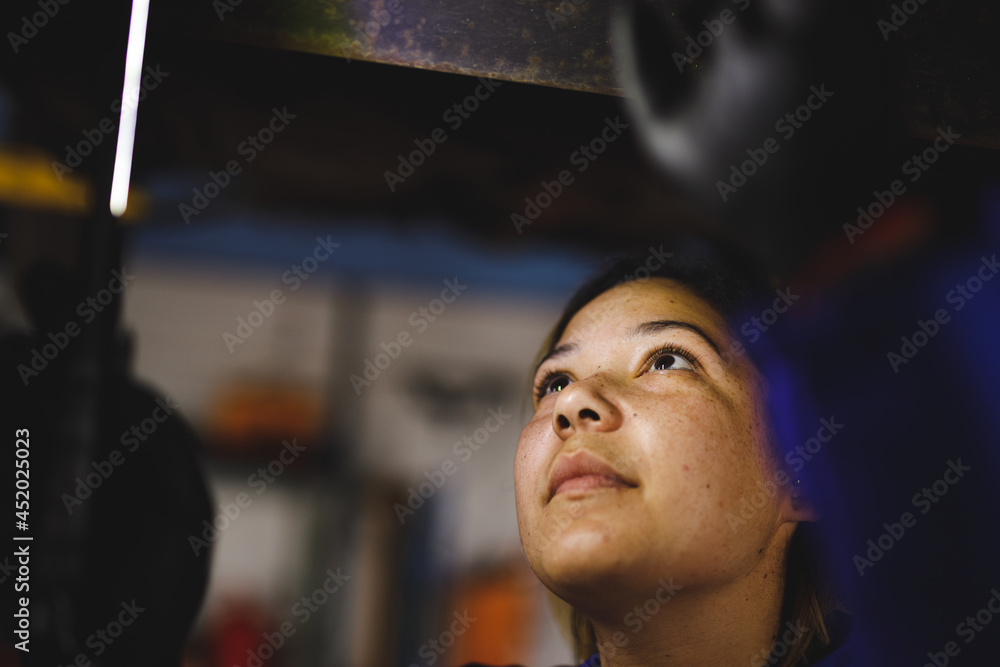 Mixed race female car mechanic wearing overalls, inspecting car Mixed race female car mechanic wearing overalls, inspecting car