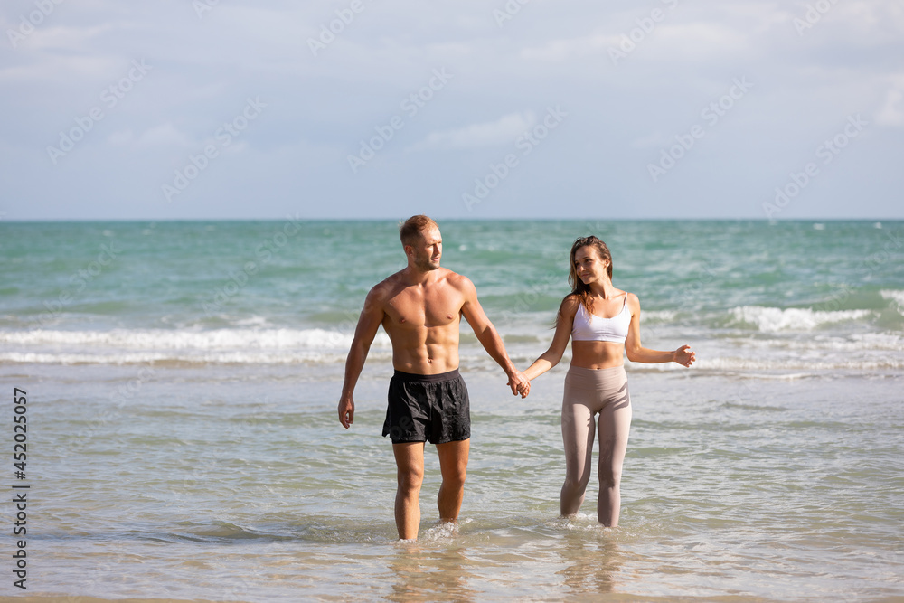 happy couple walking and splashing water on the sea in summer day happy couple walking and splashing water on the sea in summer day