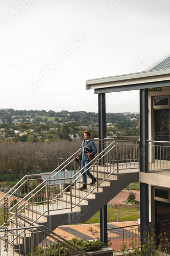 Serious caucasian male business creative walking downstairs holding notebooks photo