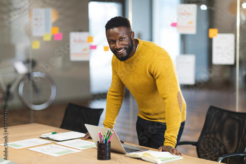 Smiling african american male business creative standing at desk and looking at camera photo