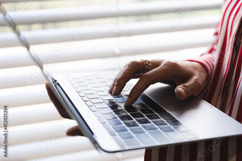 Hands of caucasian female business creative standing at window, using laptop photo