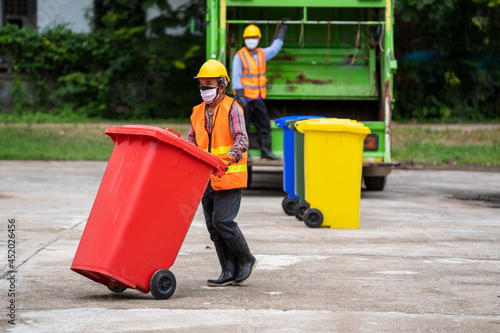 Fotografie Rubbish cleaner man working with truck loading waste and trash bin