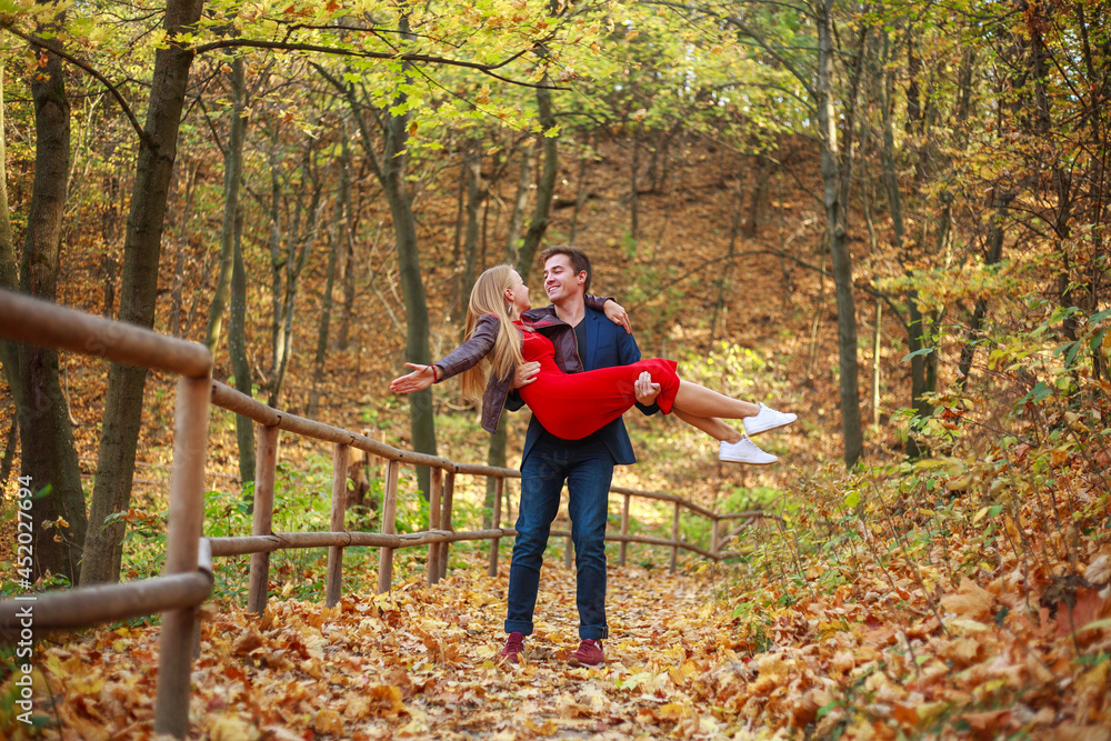 Happy young couple guy and girl enjoying nature of autumn park together Happy young couple guy and girl enjoying nature of autumn park together