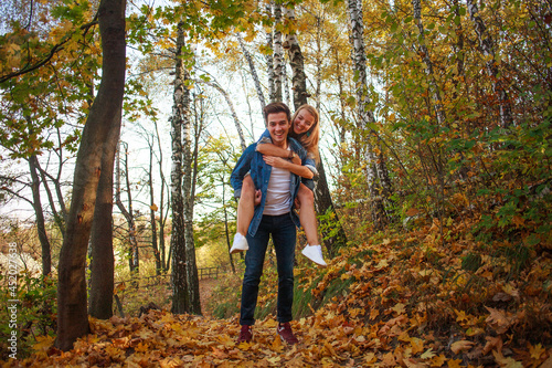 Happy young couple guy and girl enjoying nature of autumn park together