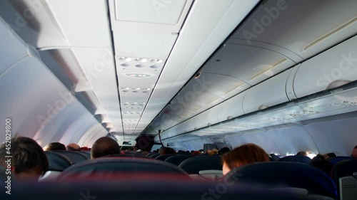 Airliner passenger cabin with different people waiting for takeoff and tourists sit on seats keeping distance backside view photo