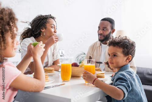 african american woman drinking coffee during breakfast with family