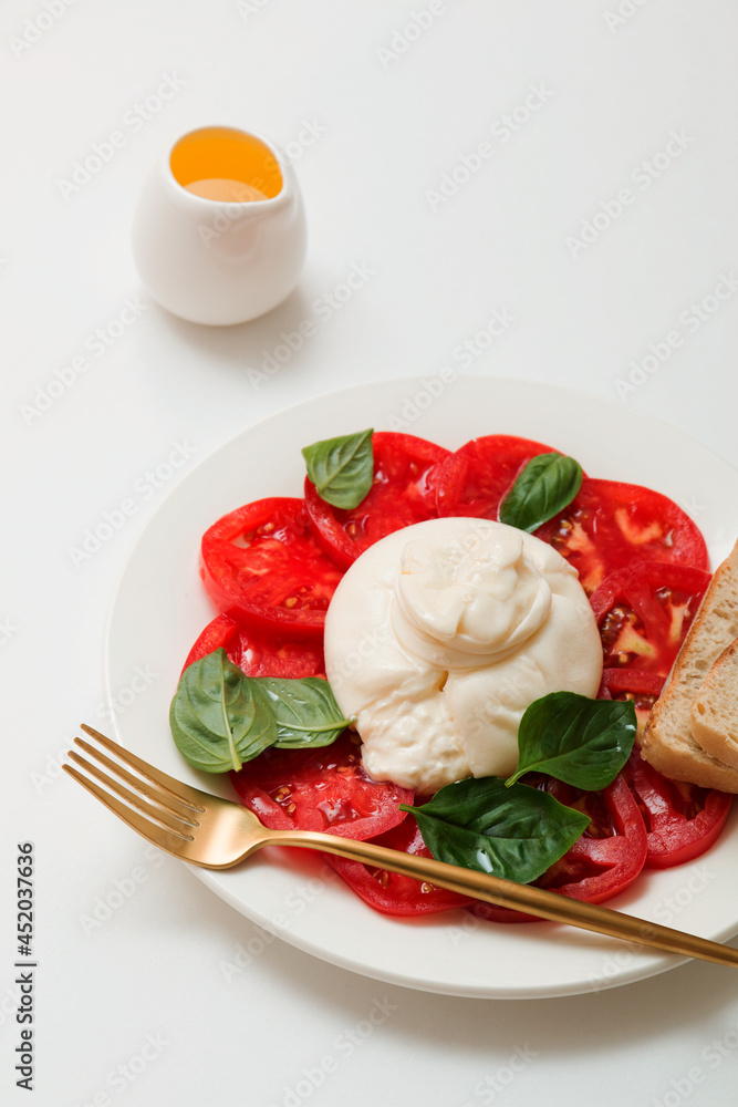 Delicious fresh cheese made from cream and milk - burrata. Italian tender cheese with tomato and greens salad, bread and olive oil. Delicious fresh cheese made from cream and milk - burrata. Italian tender cheese with tomato and greens salad, bread and olive oil.