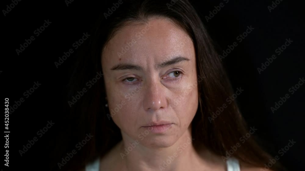 portrait of a brunette on a dark background. the woman closes and opens eyes one at a time and moves them in different directions. close-up portrait of a brunette on a dark background. the woman closes and opens eyes one at a time and moves them in different directions. close-up
