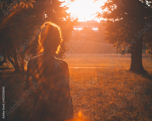 piękna dziewczyna spacerująca w pomarańczowych romantycznych promieniach zachodzącego słońca