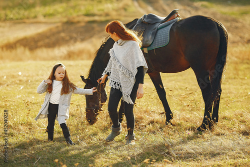 Mother and daughter in a field playing with a horse © prostooleh