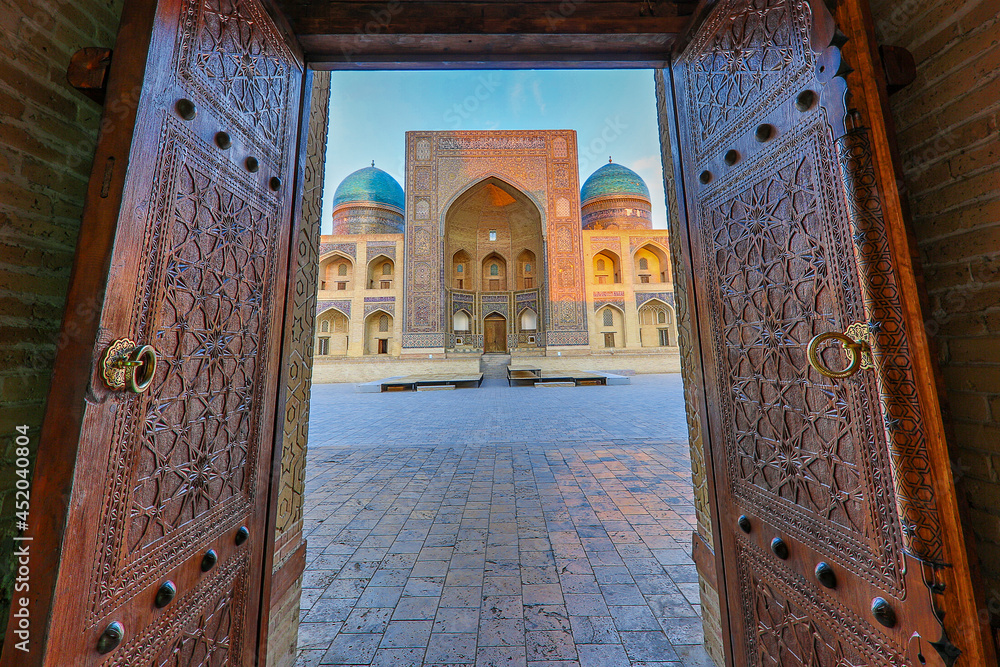 Φωτογραφία View over Poi Kalon theological school, through wooden doors of the mosque in Bukhara, Uzbekistan