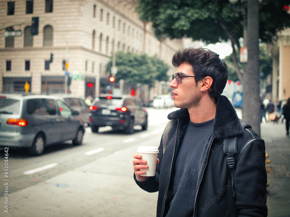 Fototapeta premium Attractive young man in modern city center drinking coffee